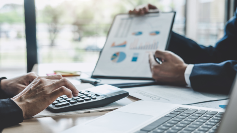 Ottimizzazione aziendale con holding, fondazioni non profit e stati offshore-friendly negli USA - L'immagine mostra un incontro di business con due professionisti in giacca che analizzano grafici finanziari e utilizzano una calcolatrice per pianificare strategie di ottimizzazione fiscale e strutture societarie. Us Company Advisor assiste le aziende italiane nella creazione di holding, strutture offshore e fondazioni non profit per operare in modo efficiente e conforme nel mercato statunitense.