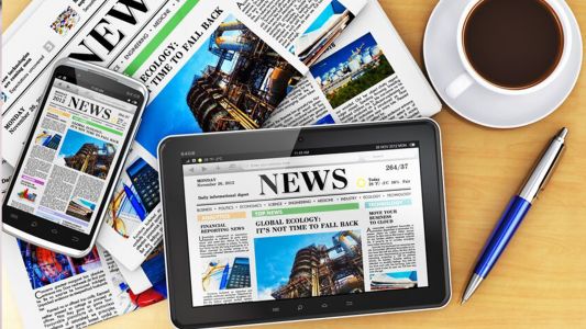 Press Office and Corporate Communication Management - The image shows newspapers, a tablet and a smartphone with digital news, accompanied by a pen and a cup of coffee on a desk. This represents the dissemination of press releases and the management of corporate reputation. Us Company Advisor helps Italian companies gain visibility in the United States through PR, media relations and digital communication strategies.