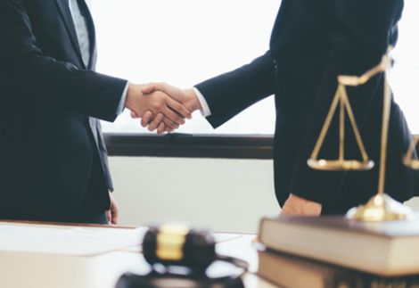 Consulenza legale per aziende negli Stati Uniti - L'immagine raffigura due professionisti in abiti formali che si stringono la mano in un ufficio, simbolo di accordi commerciali e partnership. In primo piano, una bilancia della giustizia e un martelletto da giudice rappresentano il supporto legale. Us Company Advisor offre assistenza giuridica per aziende italiane che vogliono operare nel mercato USA, garantendo conformità normativa e tutela legale.